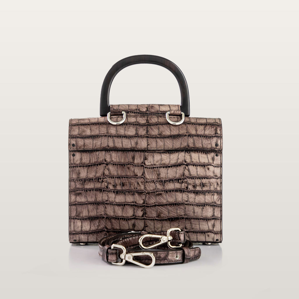 Brown textured handbag with black handle and matching strap on a light gray background