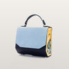 Handbag with a light blue top section and black bottom section on a beige background