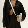 Person wearing a black outfit holding a white handbag with wooden accents.