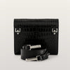 Black crocodile-patterned handbag with matching belt on a light gray background