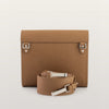 Brown leather handbag with matching strap on a light beige background