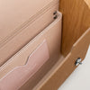 Close-up of a beige leather wallet with a wooden background