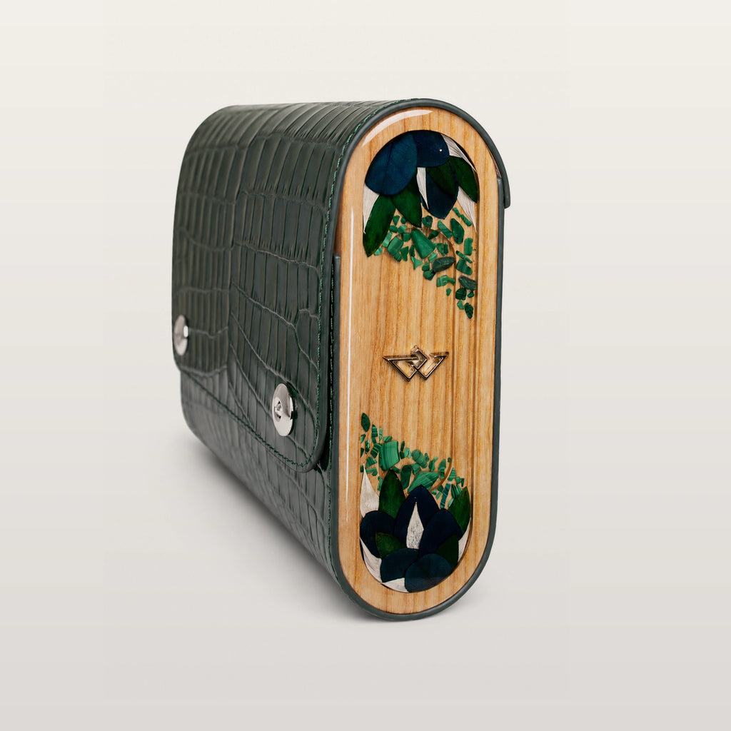 Green textured clutch with wooden panel featuring floral design on a light gray background