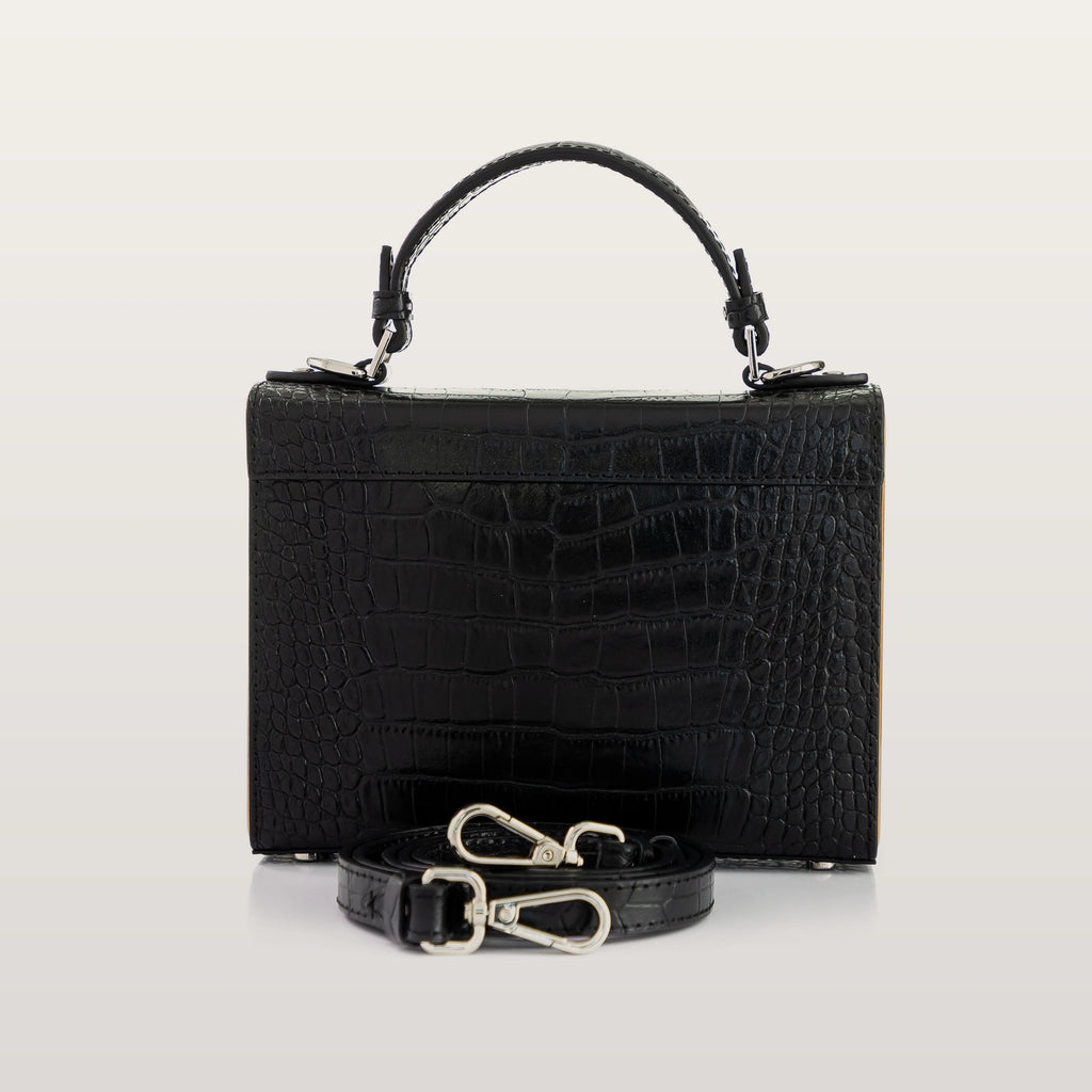 Black crocodile-patterned handbag with a strap on a light gray background